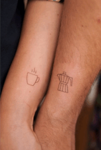 Couple tattoos featuring a steaming coffee cup and a coffee maker, symbolizing shared love for coffee and connection.